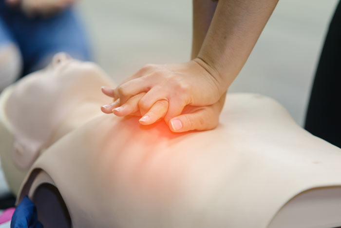 Hands performing CPR on a training mannequin demonstrating lifesaving skills.